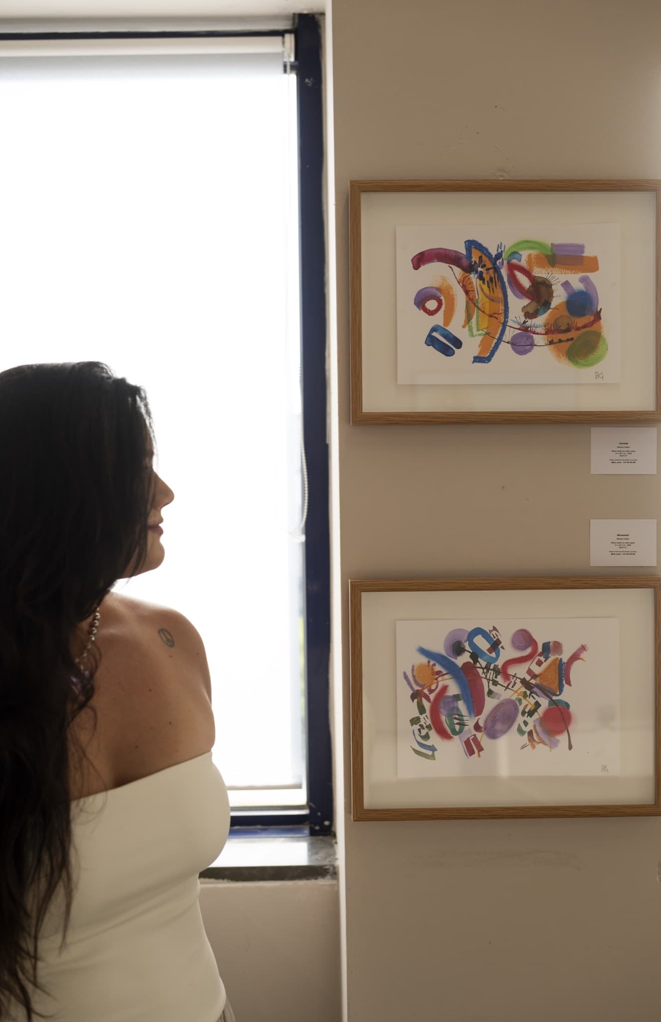Bianca Castro with two framed works on paper, Jornada and Movement, at Intensity & Relief